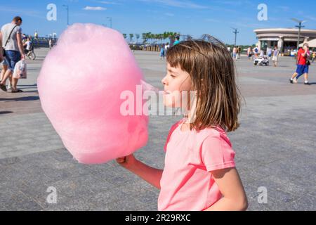 Girl eating cotton candy floss outdoors on a sunny summer day Stock Photo