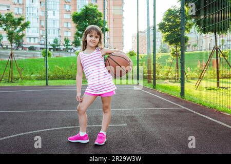 A girl on the playground with a ball plays basketball. Sport lifestyle Stock Photo