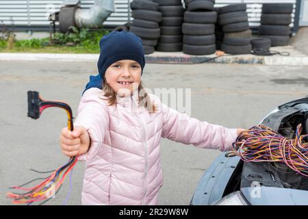 A child mechanic changes fuses in a car. Repair services in car service Stock Photo