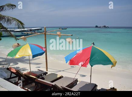 Colourful sun umbrellas on Koh Lipe beach in Thailand. Stock Photo