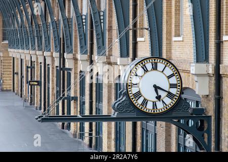 London, England-August 2022; View of the large analog clock on the platform of Kings Cross station with brick side of concourse Stock Photo