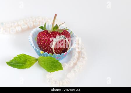 Jewelry set with diamonds in a paper cupcake mold with a juicy strawberry inside. Stock Photo