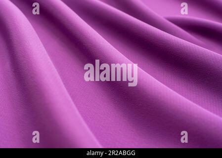 Texture of a smooth luxurious, elegant fabric in burgundy, purple, red. Purple satin or silk fabric with folds and waves Stock Photo