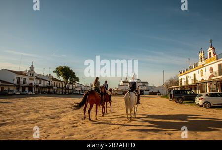 Riders through a sandy street in the town of El Rocio Stock Photo