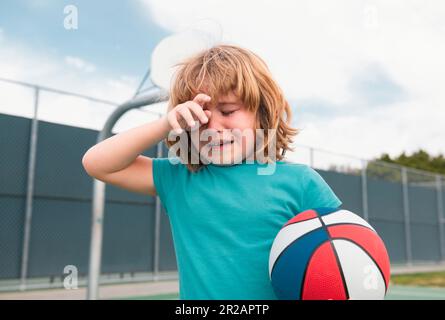 Boy cries of resentment and grief. Little boy alone, lonely with ball. Loneliness kids. Sad child boy portrait. Stock Photo