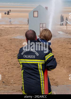 Houlgate, France May 2023. A firefighter with a hose to put out fires during a children's show on the beach in Houlgate Normandy Stock Photo