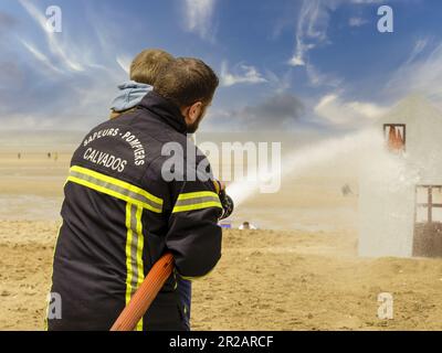 Houlgate, France May 2023. A firefighter with a hose to put out fires during a children's show on the beach in Houlgate Normandy Stock Photo