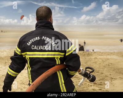 Houlgate, France May 2023. A firefighter with a hose to put out fires during a show on the beach in Houlgate, Normandy Stock Photo