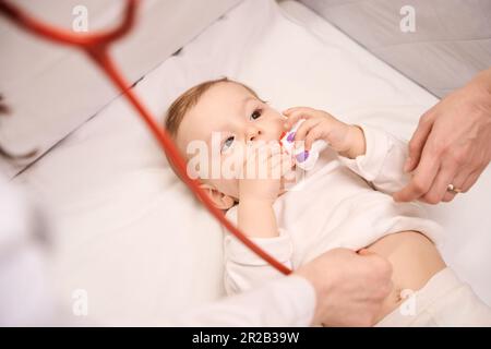 Infant in crib being examined by pediatric doctor with stethoscope Stock Photo