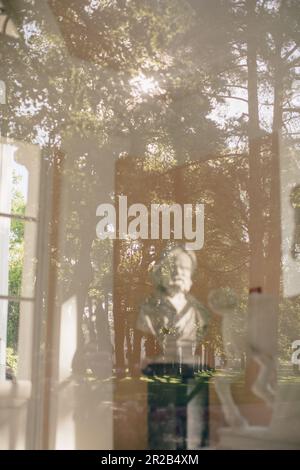 Statue behind the window of glass with reflection of beautiful garden ...
