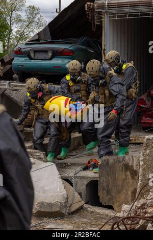U.S. Marines on a search and rescue team with Alpha Company,  Chemical Biological Incident Response Force, carry a simulated casualty out of a crushed vehicle during Exercise Guardian Response 2023 at the Muscatatuck Urban Training Center, Indiana, May 2, 2023. Exercise Guardian Response is an annual exercise that provides realistic training in a multi-domain environment, allowing units to exercise their pre-mobilization and pre-deployment capabilities to maintain readiness for chemical, biological, radiological, nuclear, or explosive disasters. (U.S. Marine Corps photo by Staff Sgt. Jacquelin Stock Photo