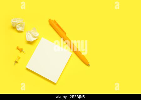 Pen with sticky notes and pins on yellow background Stock Photo