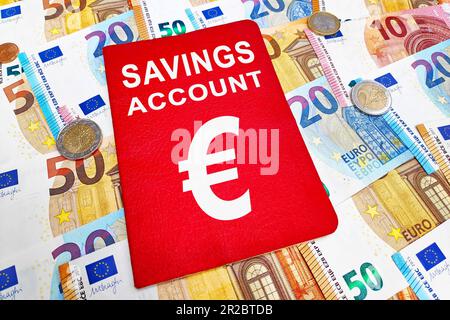 Savings account passbook atop of a stack of euro banknotes and coins. Stock Photo