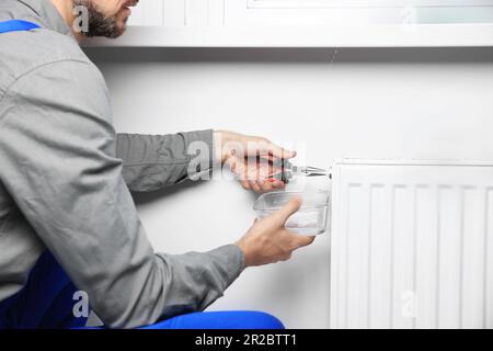 Professional plumber using pliers while preparing heating radiator for winter season, closeup Stock Photo