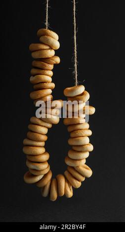 Bunch of delicious ring shaped Sushki (dry bagels) hanging on black background Stock Photo