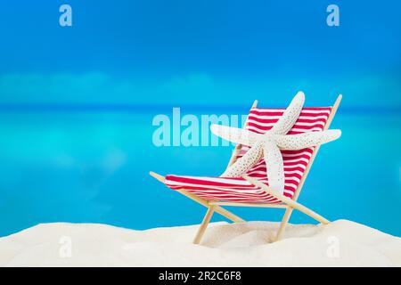 White starfish on striped red sunbed on sand of beach behind sea. Summer, travel vacation in hot countries. Copy space Stock Photo