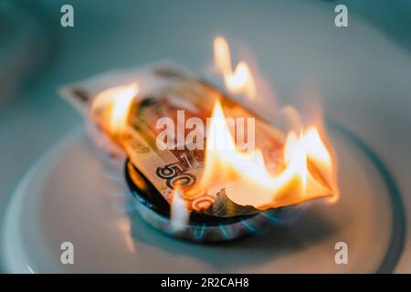 Russian ruble is burning in fire. concept the rise in the price of gas in Russia. a bill of 5000 rubles burns in a fire on a gas stove. Expensive gas Stock Photo