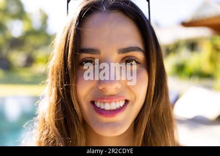 Portrait of smiling caucasian fit woman standing by pool in sunny garden Stock Photo