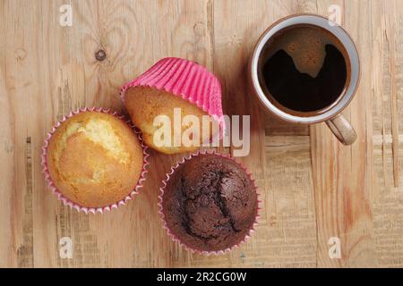 Three muffins and coffee and cup of coffee on wooden table, top view Stock Photo