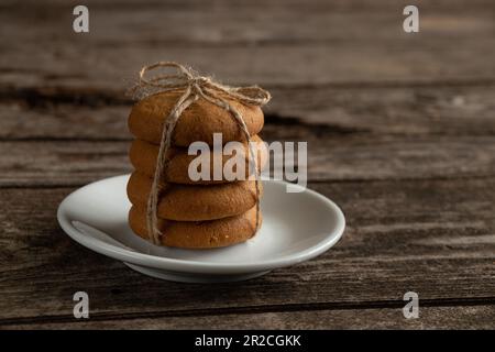 a stack of tied cookies with a rope lies on an old wooden table Stock Photo