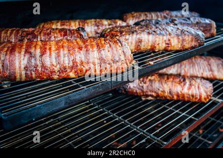 Large barbecue smoker grill at the park. Meat and bacon prepared in barbecue smoker. Stock Photo