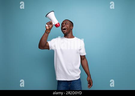 enthusiast 30 year old american male adult in white t-shirt speaks loudly using megaphone Stock Photo