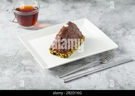 Dessert Cake from Malaga on stone table. Cake with banana inside, covered with chocolate sauce and hazelnuts Stock Photo