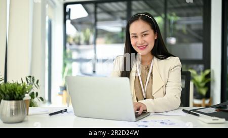 Portrait of a beautiful millennial Asian businesswoman or female accountant sits at her office desk in the office. Stock Photo