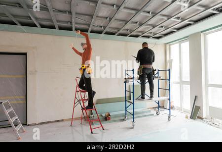 Builder fastens profile using cordless screwdriver Stock Photo