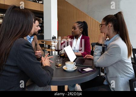 Group of young business people, managers, owners of a small company new to the labor market, staff meeting in the cafeteria, considering expanding the Stock Photo