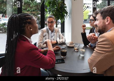 Group of young business people, managers, owners of a small company new to the labor market, staff meeting in the cafeteria, considering expanding the Stock Photo