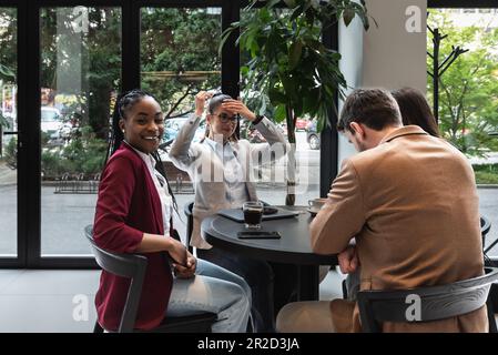 Group of young business people, managers, owners of a small company new to the labor market, staff meeting in the cafeteria, considering expanding the Stock Photo