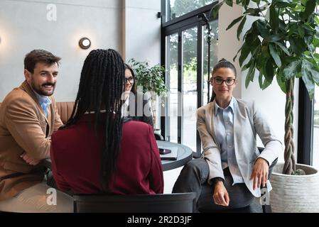 Group of young business people, managers, owners of a small company new to the labor market, staff meeting in the cafeteria, considering expanding the Stock Photo
