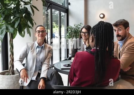 Group of young business people, managers, owners of a small company new to the labor market, staff meeting in the cafeteria, considering expanding the Stock Photo