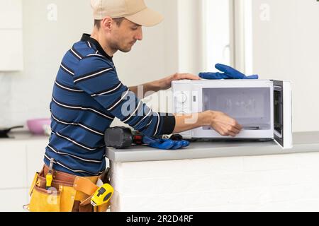 Young repairman fixing and repairing microwave oven. Stock Photo