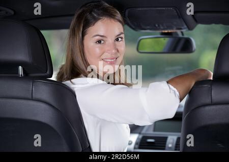 young and beautiful woman looking back inside of a car Stock Photo