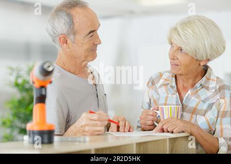 senior couple using electronic drill install cabinet Stock Photo