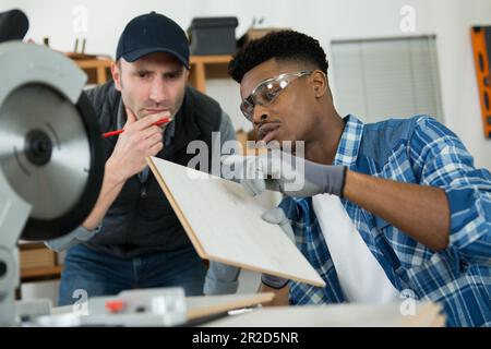 student and teacher in carpentry class using circular saw Stock Photo