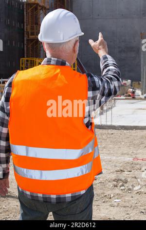 senior builder in hardhats pointing outdoors Stock Photo