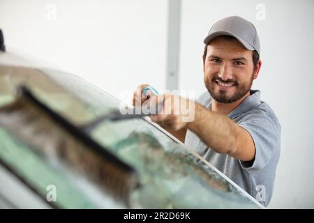 happy worker cleans a car with a brush Stock Photo