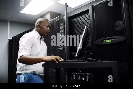 Engineer, black man or coding on laptop in server room for big data, network glitch or digital website. Code, IT support or technician typing on Stock Photo