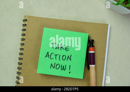 Concept of Take Action Now! write on sticky notes isolated on Wooden Table. Stock Photo