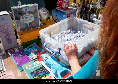 young girl pick tickets from bucket tombola stand at a local community summer fair simonswood england uk Stock Photo