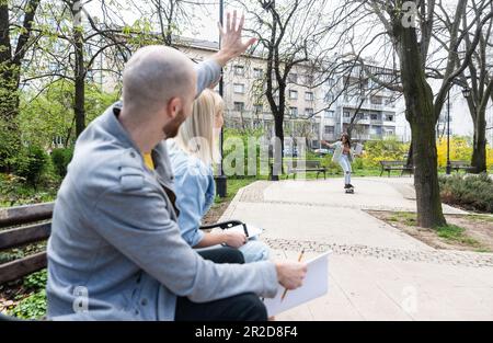 Young business people are sitting in the park on a bench having a staff meeting looking for premises or an apartment for rent to move their small comp Stock Photo