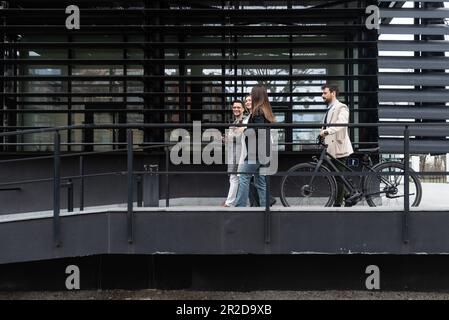 Young business people businessman and businesswoman walk from office building to building between meetings where they train employees to better and mo Stock Photo