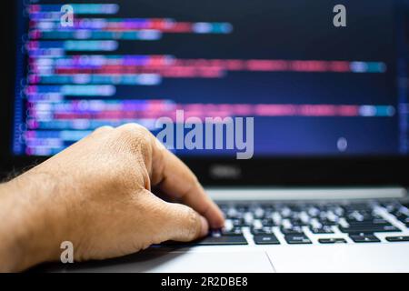 The programmer's hand is writing the source code. Programmers write programs for use with internet business services. The programming code displayed o Stock Photo