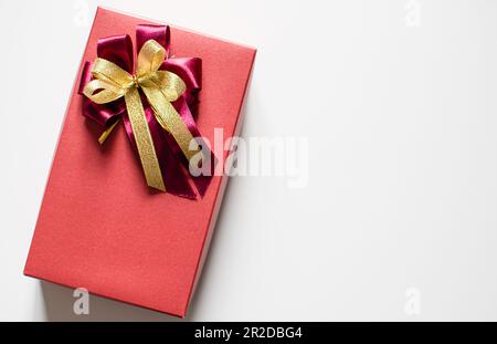 The red color Presents celebrate box with red and gold ribbons placed on a white table with copy space on the right can input text, take close-up phot Stock Photo