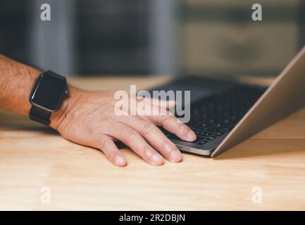Man uses his finger to press button to turn off, closed, shut down laptop computer on desk, before going home for saving energy, save global environme Stock Photo