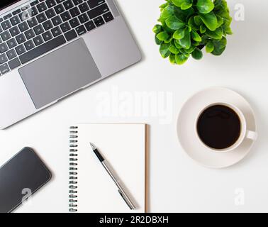 Laptop and coffee cup on a white table in the office. Working concept using technology, smartphones, notebook, internet. Crop, Close up, top view whit Stock Photo