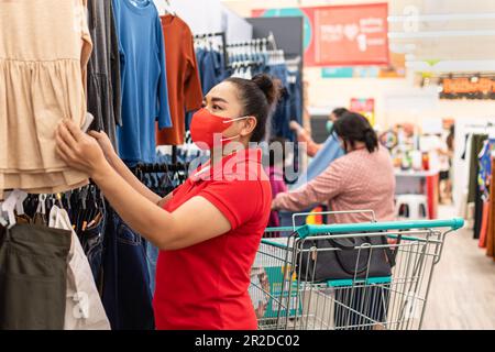 Close-up, Woman wearing mask who chose clothes for her special day In Women's apparel department of a supermarket on a casual day, Concept for shoppin Stock Photo